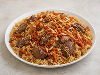 Pulao afgano con cordero, zanahorias caramelizadas, pasas rubias y almendras fileteadas