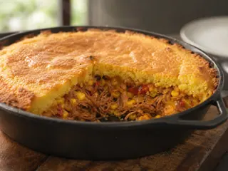 Cazuela de cerdo desmenuzado con pan de maíz, cobertura dorada y relleno de barbacoa
