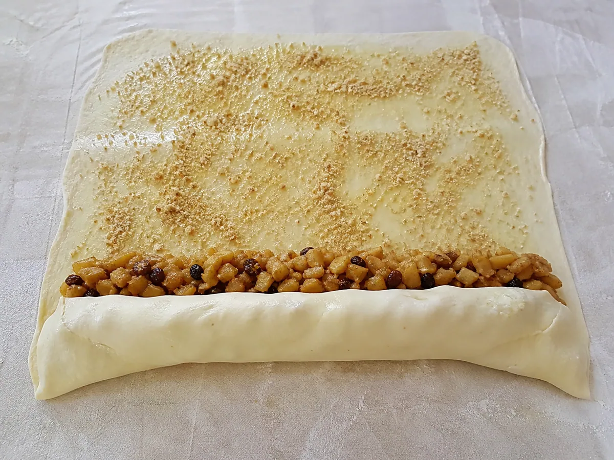 Austrian apple strudel with tucked ends and the first dough turn folded over the filling