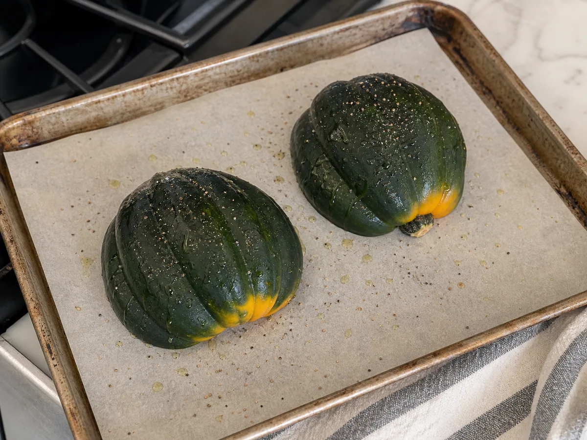 Fork-tender roasted acorn squash halves on a parchment-lined baking sheet before filling