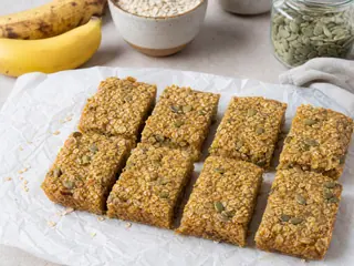 Torre de barritas de desayuno de plátano y mijo con avena y semillas de calabaza visibles
