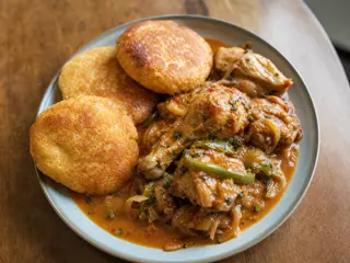 Pollo beliceño guisado en coco con Johnny cakes