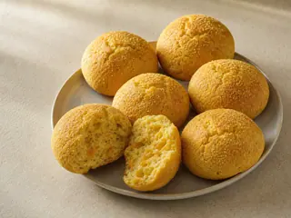 Golden Brazilian cornmeal bread rounds with crackled tops and a tender, cheese-speckled crumb