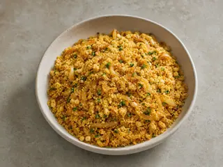 Bowl of golden Brazilian farofa with browned onions and parsley