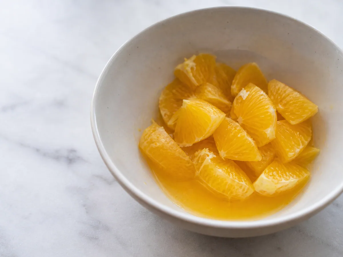 Laranjas-baía separadas em gomos limpos sobre uma tigela para salada brasileira de palmito e laranja