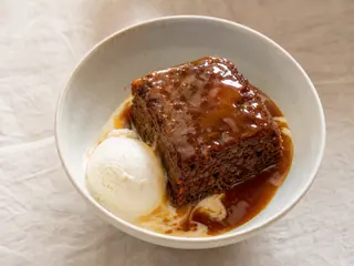 Pudín británico de toffee cubierto de salsa brillante y servido con helado de vainilla