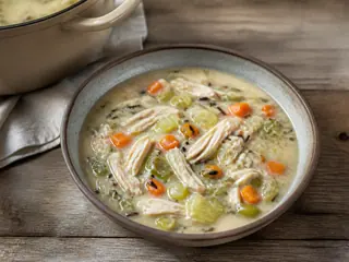 Bowl of creamy chicken and wild rice soup with leeks, carrots, and parsley