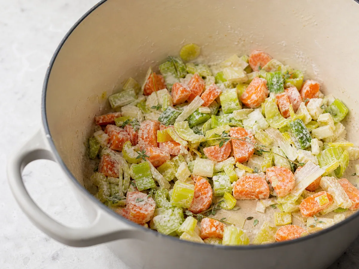 Leeks, carrots, and celery evenly coated with pale flour in the soup pot