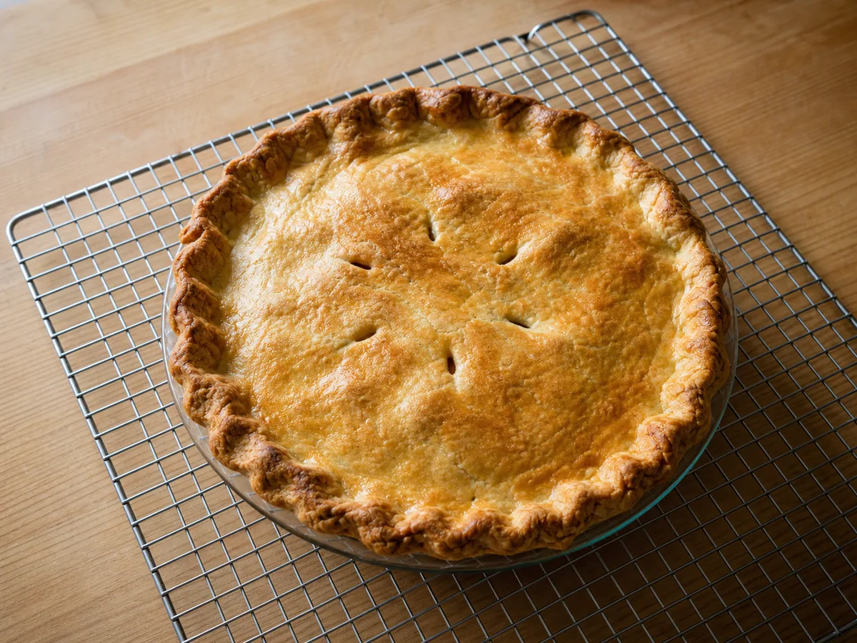 Tourtière canadiense bien dorada, con vapor saliendo por los cortas de la masa