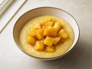 Tazón de atole cremoso de maíz cubierto con piña al jengibre y limón verde
