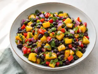 Tazón de ensalada caribeña de mango y frijoles negros con pimiento rojo y cilantro