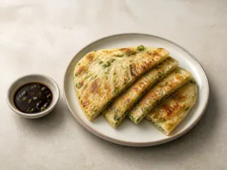Pilha de fatias crocantes de panqueca chinesa de cebolinha com molho de shoyu e vinagre