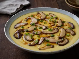 Tigela rasa de ovos chineses no vapor com cogumelos shiitake e cebolinha