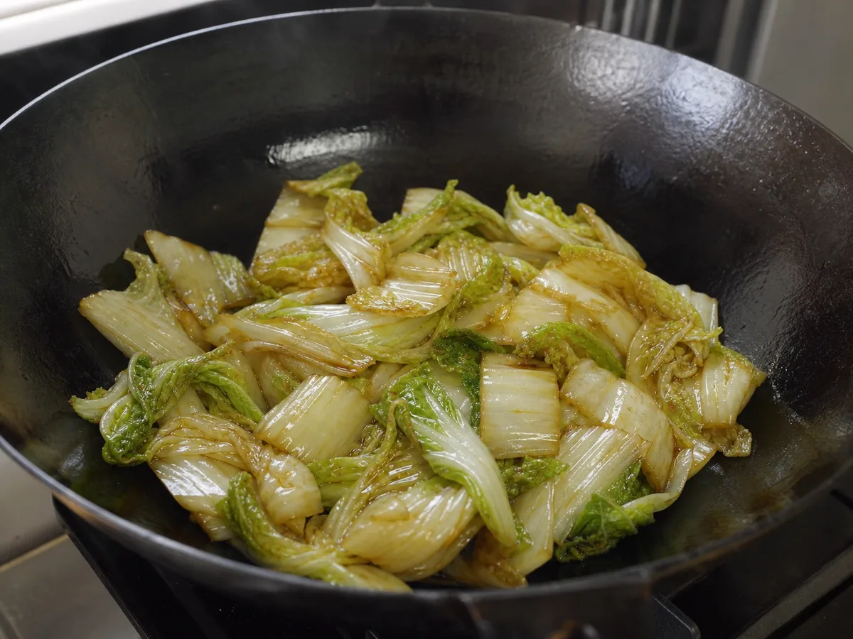 Repolho Napa salteado e brilhante, com folhas verdes murchas e nervuras claras macias, porém crocantes, numa wok