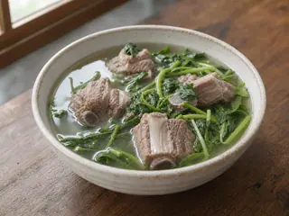 Tazón de sopa china de berros y costillas de cerdo con caldo claro y hojas tiernas