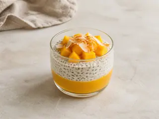 Pudim de chia com coco e manga em camadas, coberto com manga em cubos e coco torrado