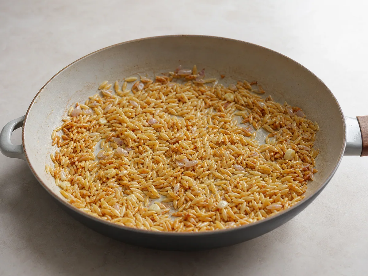 Orzo ligeramente tostado con chalotes suaves y ajo para el orzo cremoso de pollo con limón