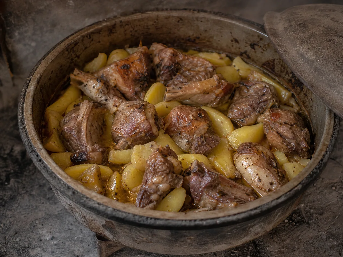 Nearly fork-tender cooked lamb peka with potatoes moved into the pan juices before browning