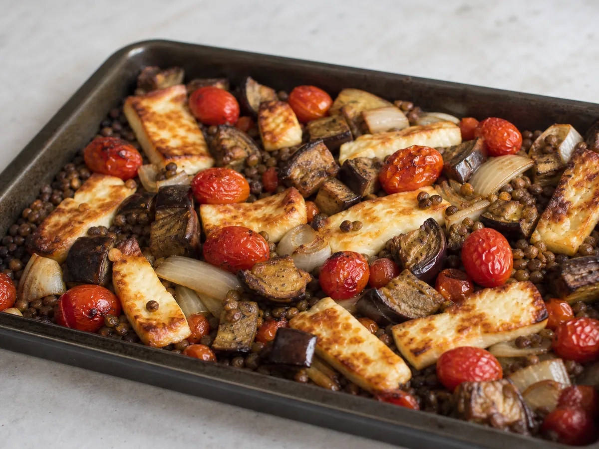 Legumes parcialmente assados, com bordas douradas e tomates estourados, após a primeira etapa de forno