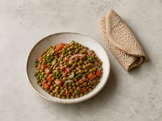 Shallow bowl of Ethiopian azifa lentil salad with tomato, red onion, jalapeño, and parsley