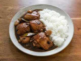 Adobo de pollo filipino con salsa brillante servido sobre arroz blanco