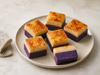 Rebanadas de pastel de yuca y ube violeta con natilla de coco y queso dorado