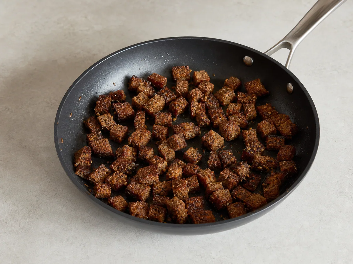 Croutons crocantes de centeio escuro com sementes de alcaravia em uma frigideira