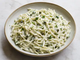 Tazón de remoulade francés de apionabo con yogur, salpicado de hierbas y alcaparras