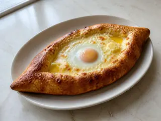 Barca dourada de khachapuri georgiano com queijo derretido, ovo bem cozido e manteiga