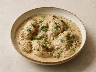 Frango satsivi à moda georgiana, servido quente, em uma tigela rasa com molho de nozes, coentro e sementes de romã