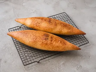 Dois pães shoti georgianos longos, com pontas bem afiladas e crosta dourada cheia de bolhas