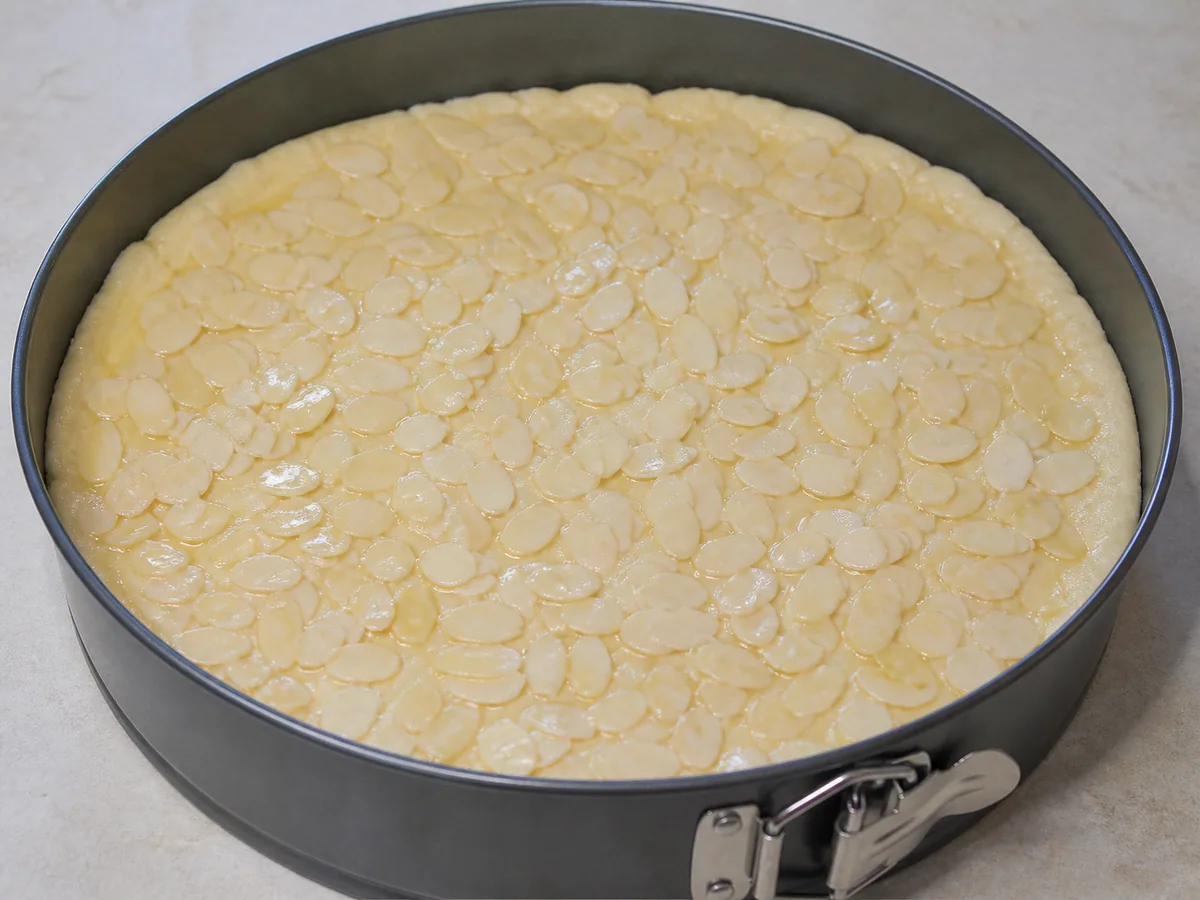 Puffy bee sting cake dough topped evenly with warm honey almonds before baking