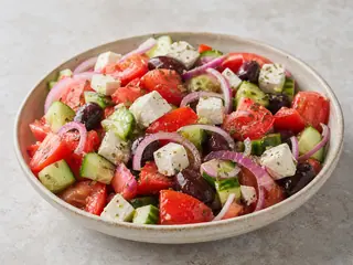 Greek village salad with tomatoes, cucumber, olives, and slabs of feta