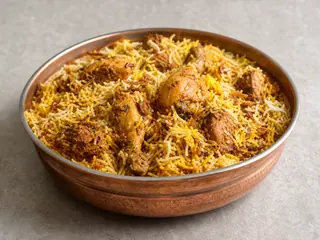 Biryani indio de pollo con arroz al azafrán, hierbas y cebollas doradas en una fuente amplia
