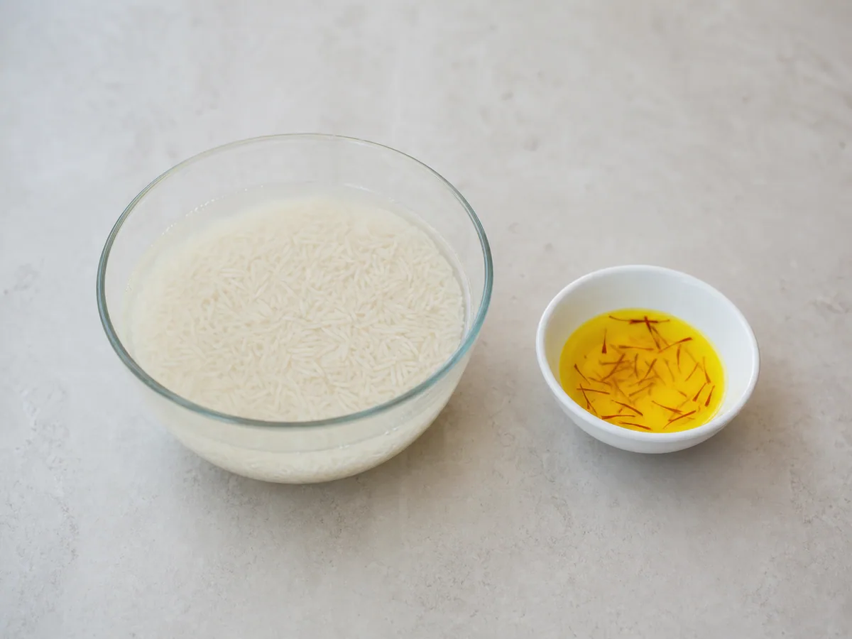 Arroz basmati escurrido y remojado junto a leche dorada con azafrán para el biryani indio de pollo