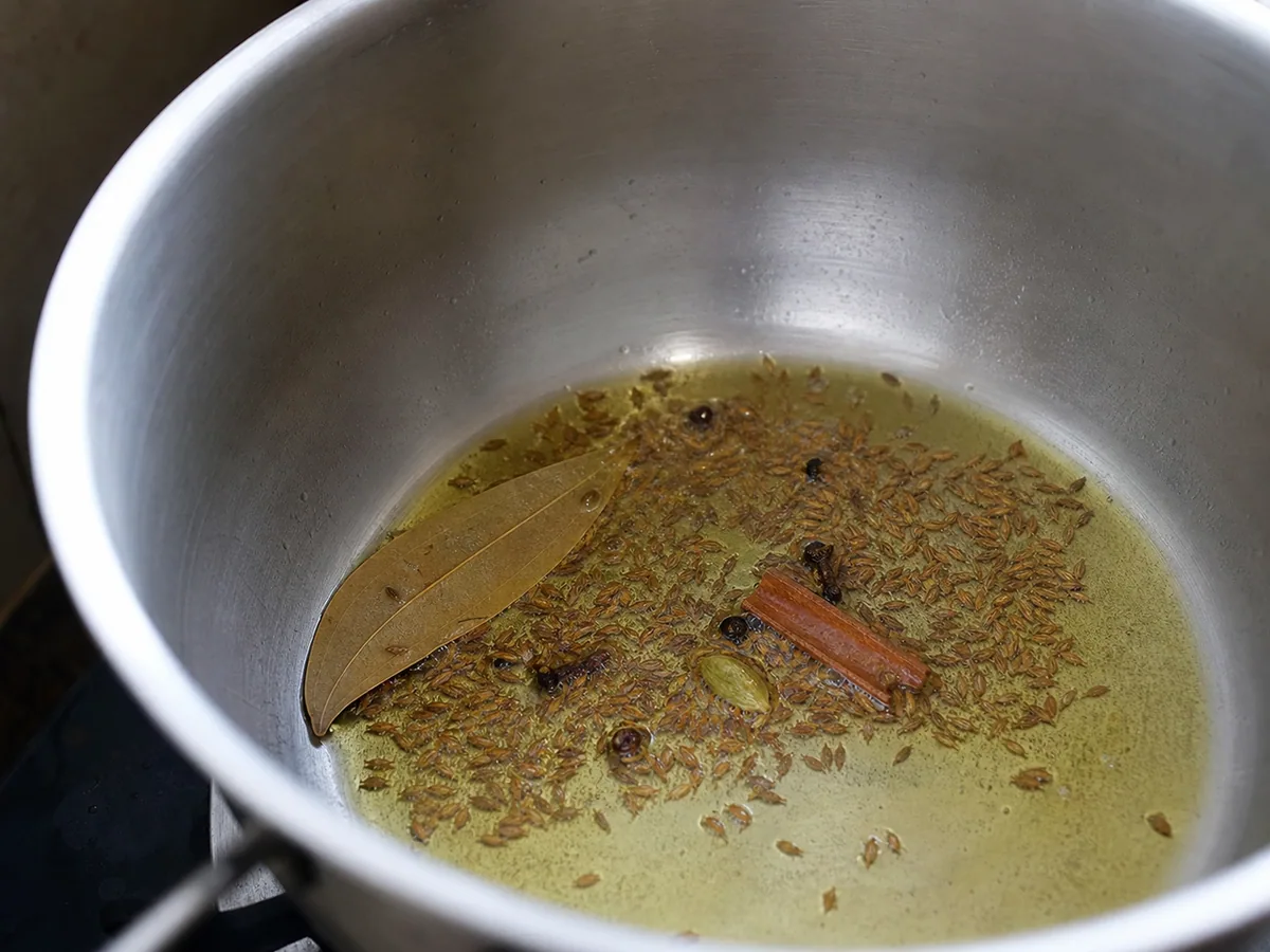 Semillas de comino chisporroteeo en ghee con especias enteras para arroz jeera indio