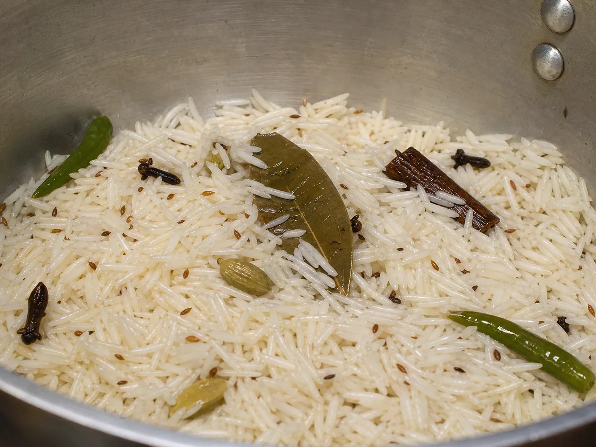 Arroz basmati brilhante envolto em cominho chiando e especiarias inteiras