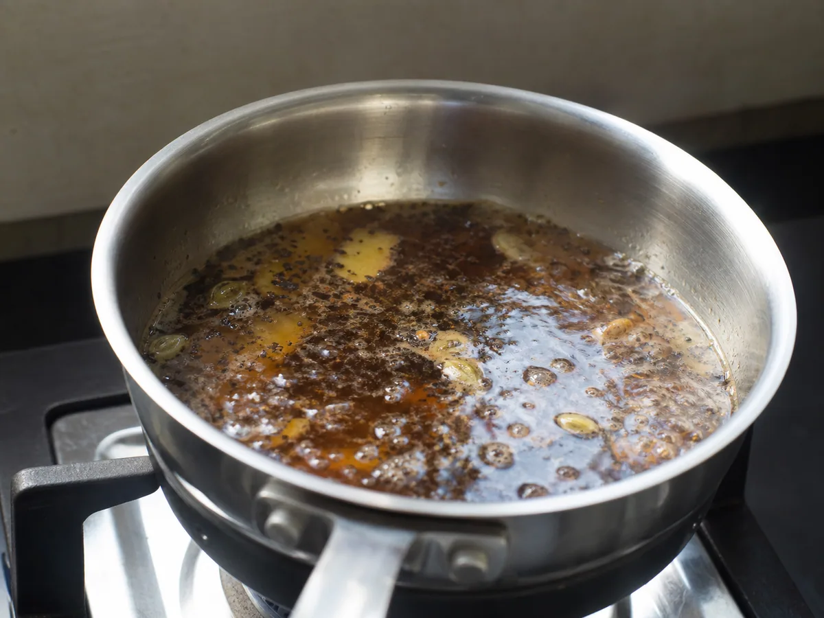 Té Assam cobrizo oscuro hirviendo con las especias del chai