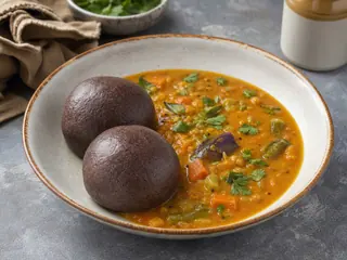 Mudde de ragi servido con sambar de verduras en un tazón sencillo