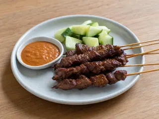 Indonesian beef satay skewers with peanut sauce and cucumber