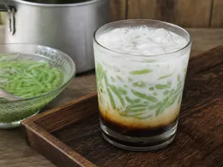 Glass of Indonesian cendol with green pandan jelly, coconut milk, palm sugar syrup, and ice