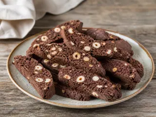 Chocolate hazelnut biscotti on a ceramic plate beside espresso
