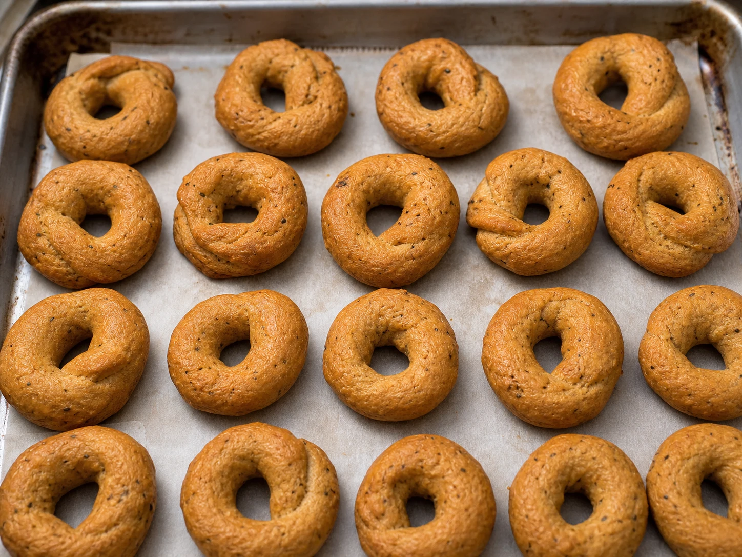 Taralli de hinojo bien dorados, secos y firmes en una charola cubierta con papel para hornear