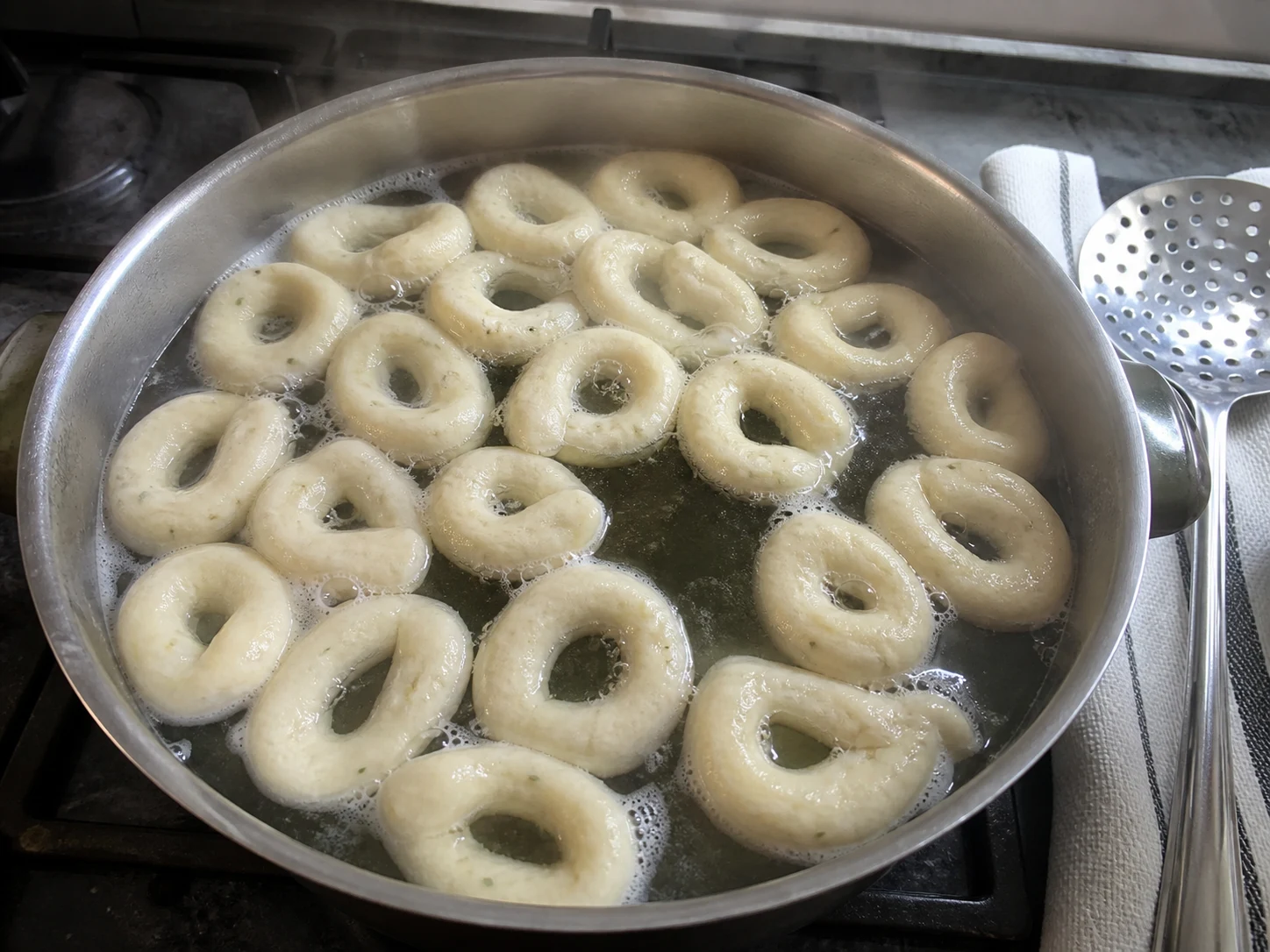 Taralli claros de hinojo flotando en la superficie durante su hervor breve