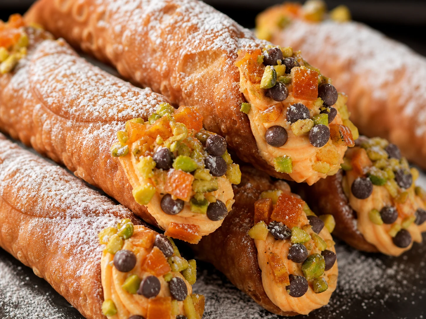 Cannoli de ricota y naranja recién rellenos, con puntas cubiertas de pistacho, antes de servir