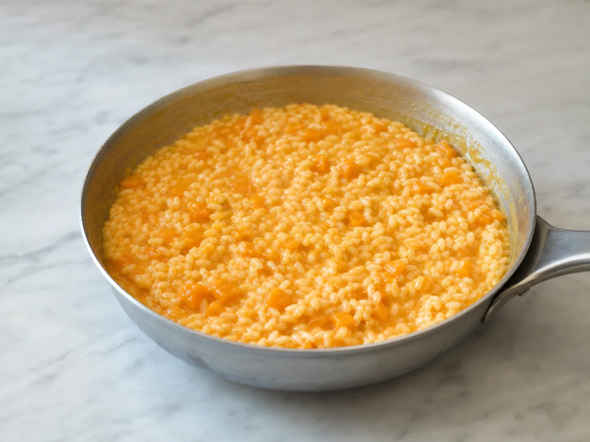 Risoto de abóbora brilhante, formando ondulações suaves na panela antes de servir