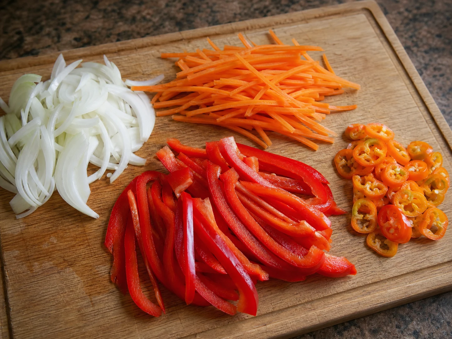 Thin onion arcs, carrot matchsticks, red bell pepper strips, and Scotch bonnet rings prepared for Jamaican escovitch fish