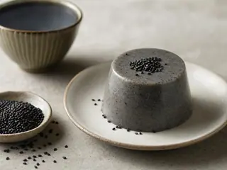 Pudín japonés de sésamo negro en una taza de cerámica con un ligero toque de sésamo por encima