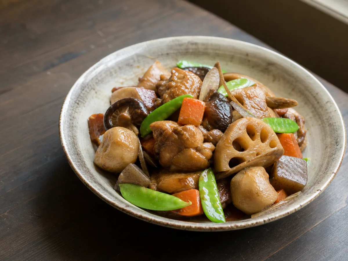 Chikuzenni japonês com frango, raiz de lótus, bardana, inhame, cenoura, shiitake, konnyaku e ervilhas-tortas em uma tigela de cerâmica