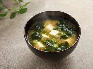 Sopa miso japonesa con cubos de tofu, wakame y cebollín en un tazón lacado